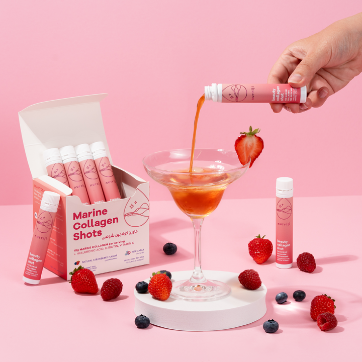 Marine Collagen Shots being poured into a cocktail with strawberries and other fruits on a pink background